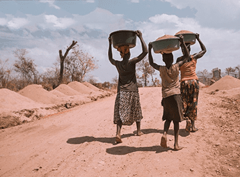 three young women carrying buckets of sand on their heads